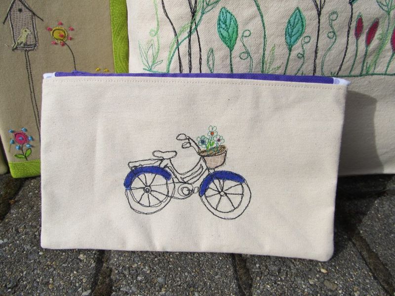 Canvas zipper pouch with a free-motion embroidered bicycle carrying a basket of flowers