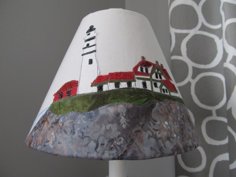 Close-up of the lampshade: appliqued lighthouse, keeper's house and stitched rocks