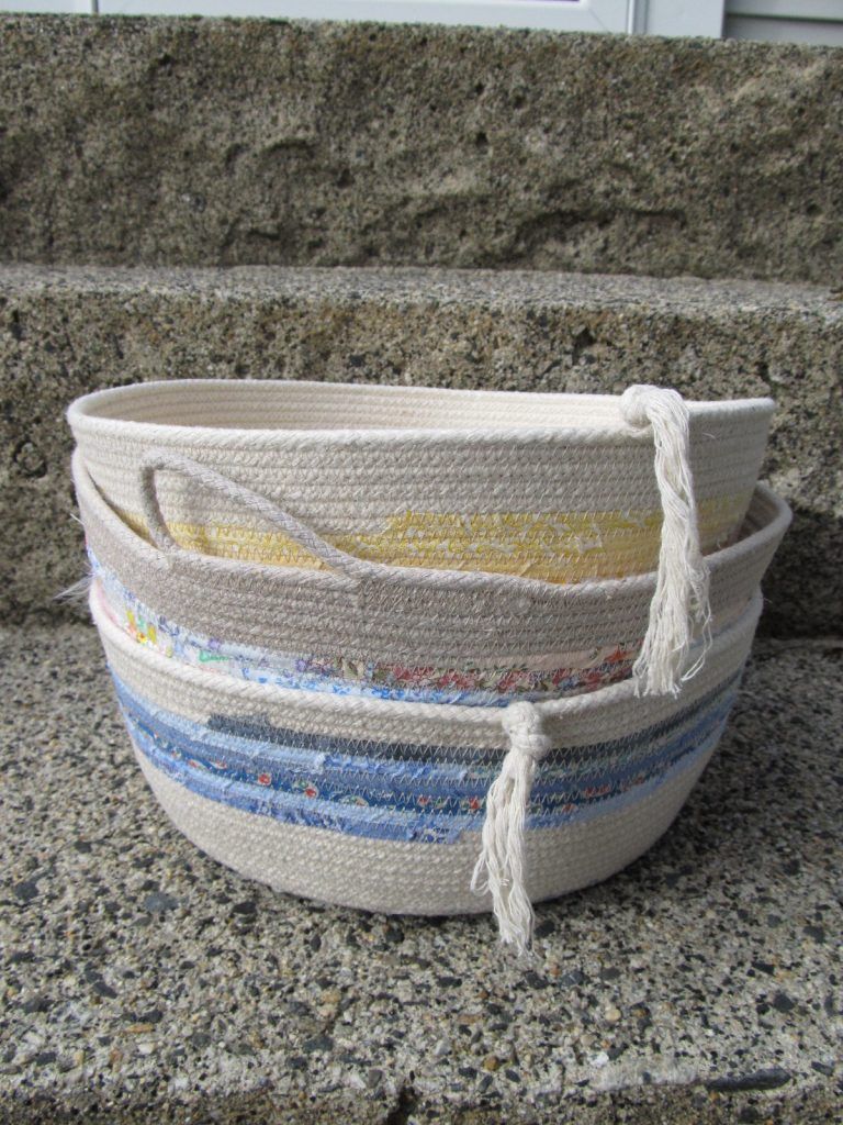 Three coiled cotton rope bowls with blue and yellow stripes, stacked on a stone step